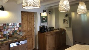 A kitchen with wooden cabinets, a coffee machine, and hanging woven light fixtures.
