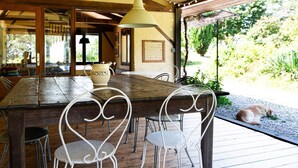 A rustic wooden table with metal chairs, a white pitcher with 'DAISIES' on it, and a hanging pendant light.