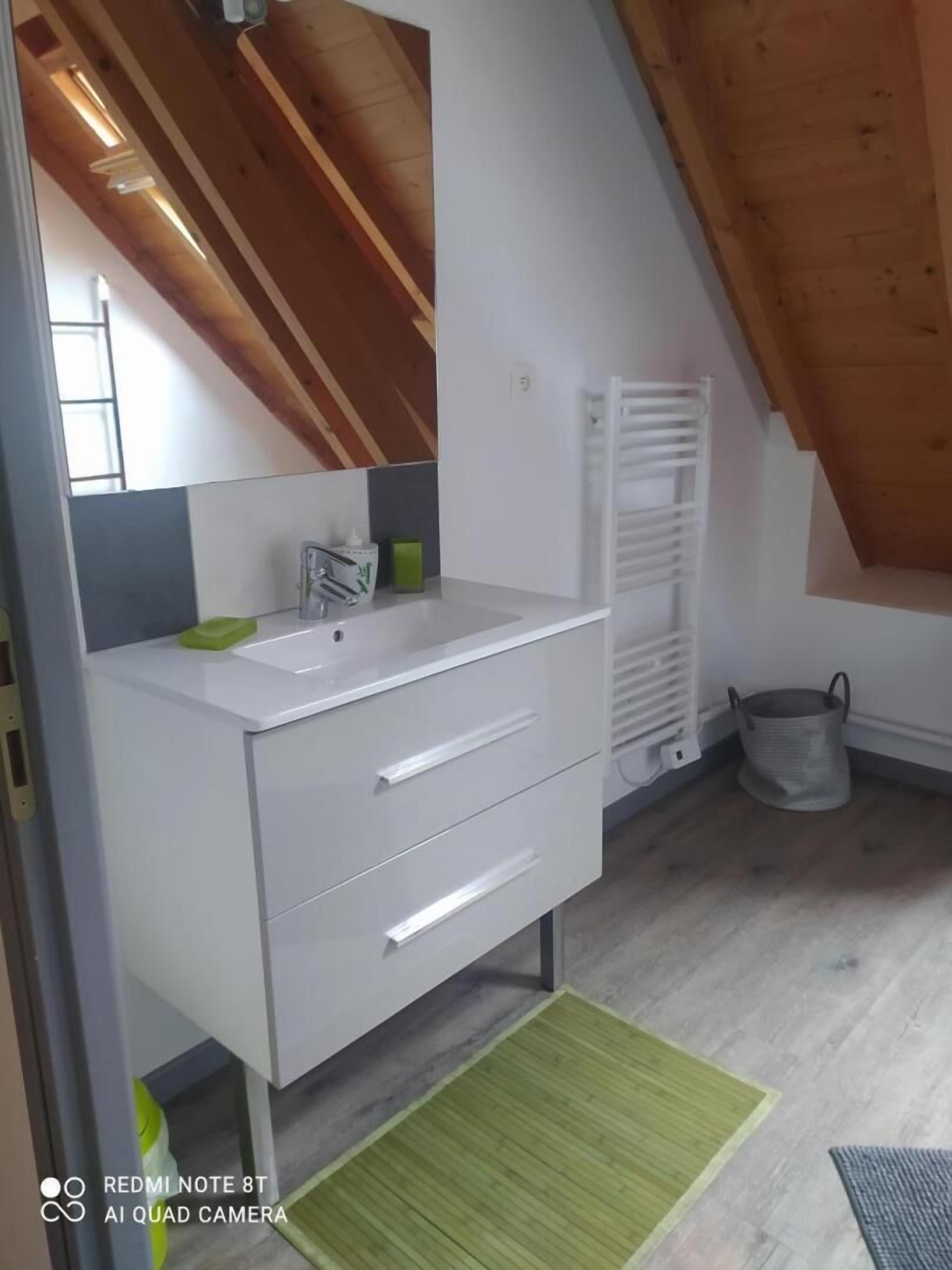 Et moderne badeværelse med en hvid kommode, et spejl og en grøn måtte.