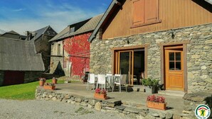 A rustic building with a stone facade, wooden exterior, and a small patio area with outdoor seating.