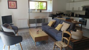 A modern living room with a sofa, chairs, a coffee table, and a TV.