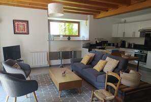 A modern living room with a sofa, chairs, a coffee table, and a TV.