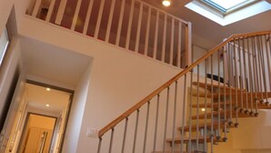 A staircase with a wooden handrail and metal balusters, leading to an upper floor with a skylight.
