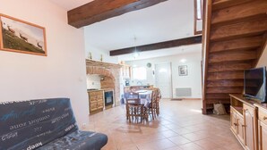 Un salon chaleureux avec un canapé, un coin repas avec une table et des chaises, une cuisine avec un mur en briques et un escalier en bois.