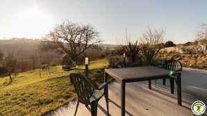 Un espacio al aire libre con mesa y sillas, rodeado de paisaje natural y cielo despejado.