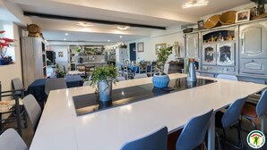 Una cocina moderna con una isla central, comedor con sillas y una encimera visible.