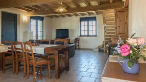 Ein rustikales Interieur mit einem Holzespeisetisch, Stühlen, einem Fernseher und einer Treppe.
