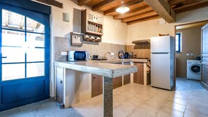 Eine kompakte Küche mit Granitplatte, Mikrowelle, Spüle und eingebautem Backofen. Im angrenzenden Raum befindet sich eine Waschmaschine.