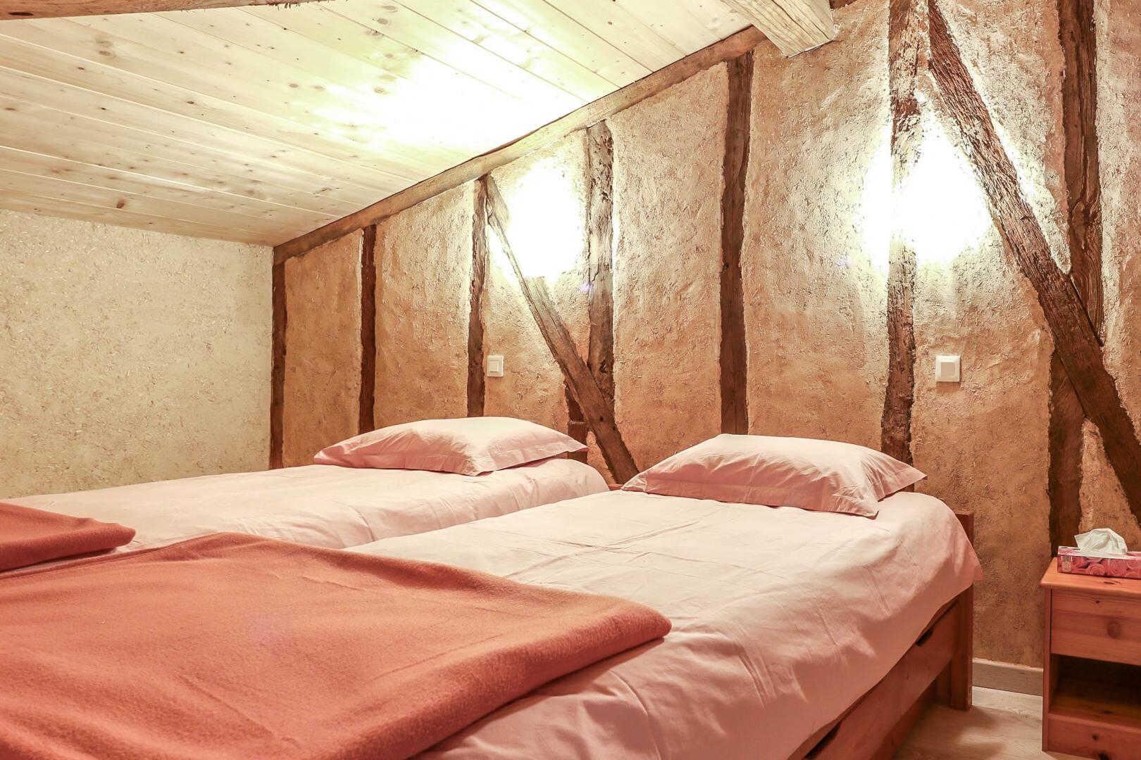 Ein Zimmer mit zwei Betten, Holzbalken und einer schrägen Decke.