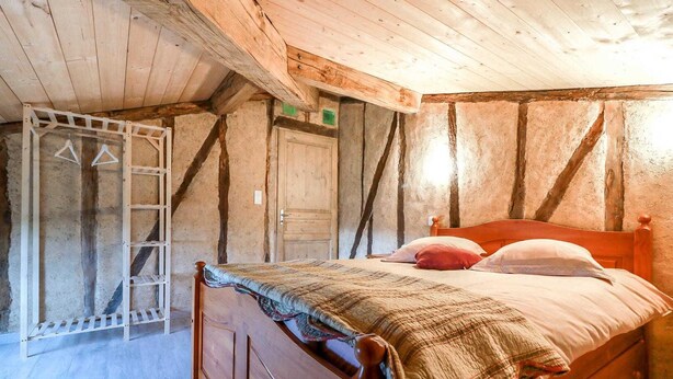 Ein rustikaler Holzraum mit einem Bett, einem Holzschrank und einer Leitern.