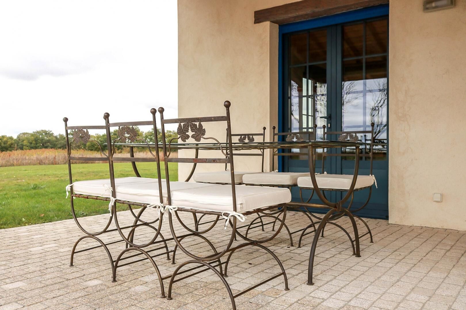A patio with a table and chairs, a blue door, and a view of the outdoors.