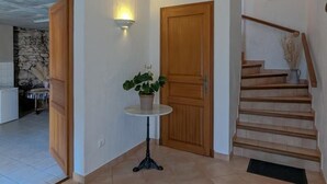 Un couloir avec une porte en bois, une petite table sur laquelle est posée une plante en pot et un escalier.