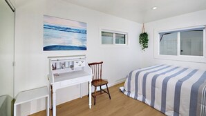 Ein Schlafzimmer mit Bett, Schreibtisch, Stuhl, Fenster und einem Bild an der Wand.