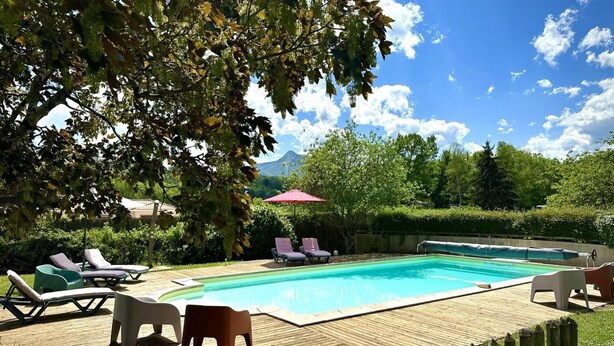 Une piscine avec des chaises longues et une terrasse en bois.