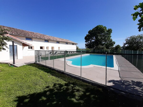 Una piscina con borde de baldosas, rodeada por una valla de metal.