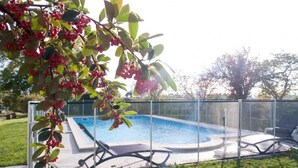 A swimming pool with a glass fence, surrounded by grass and trees. - Les Coteaux - Riolas (Riolas)