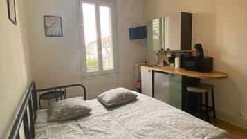 Un dormitorio con cama, escritorio y ventana.