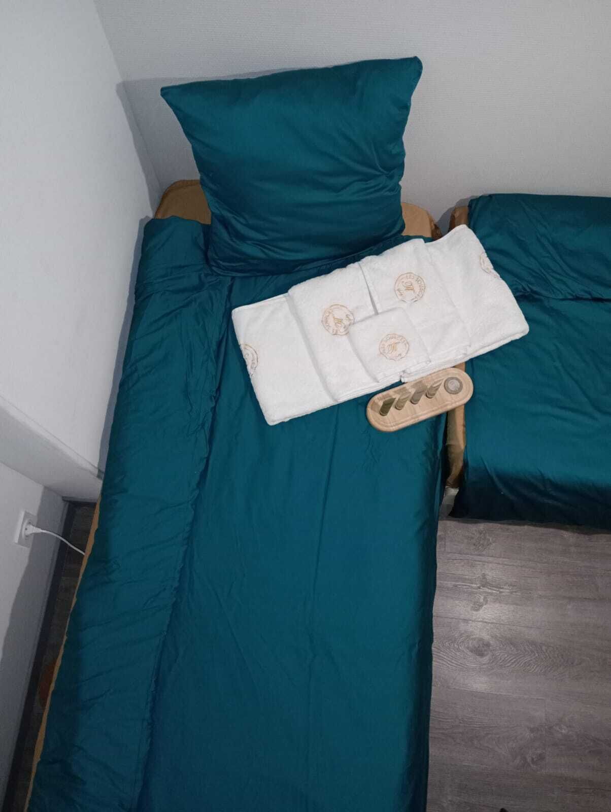 Ein Bett mit türkisblau bedeckter Bettwäsche und ein Handtuch mit einem Logo.