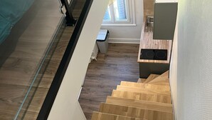 A modern interior with a wooden staircase leading to a kitchen area. - Les Sources Vichy  (Vichy)