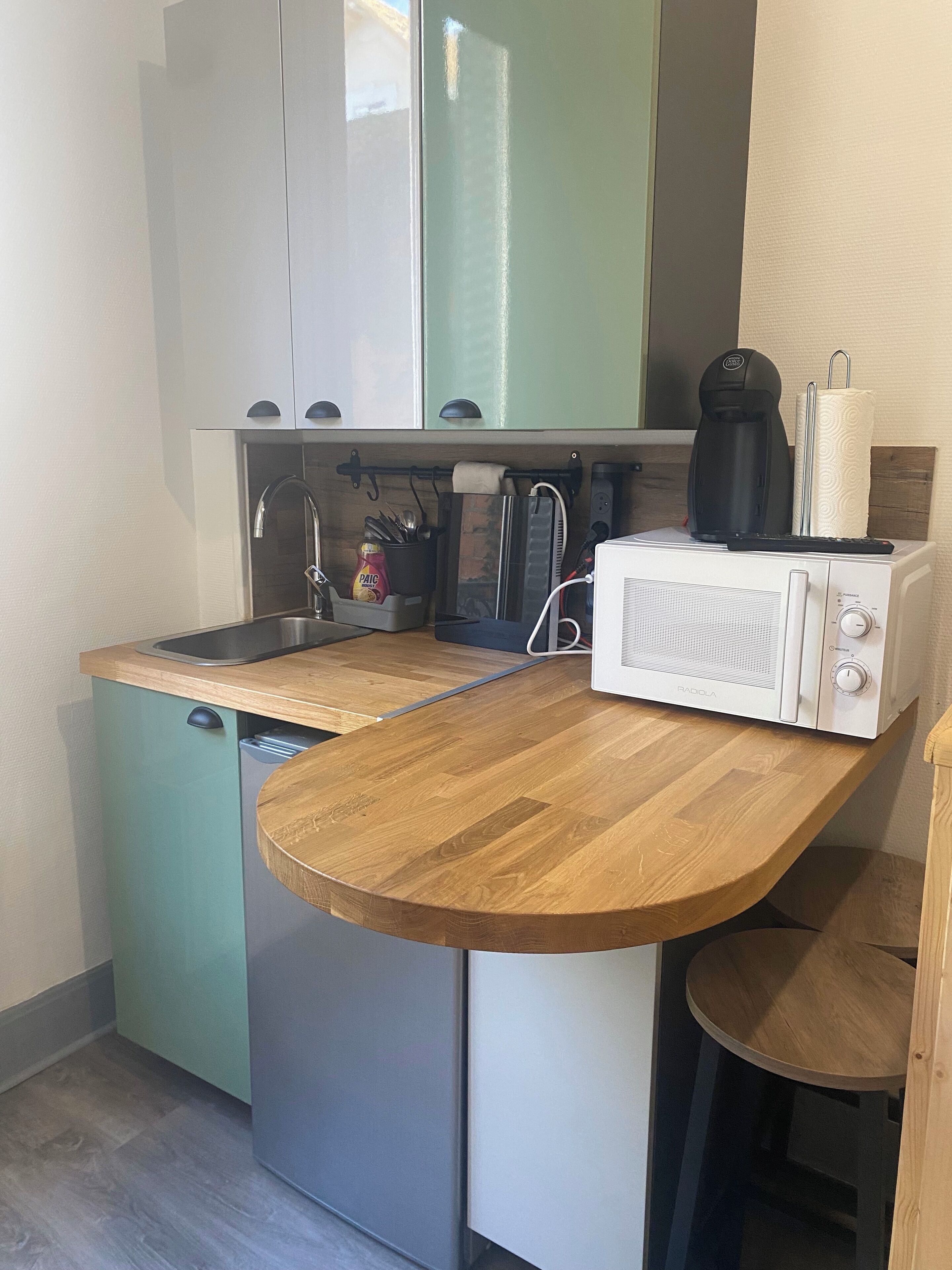 A compact kitchen with a wooden countertop, a built-in dishwasher, and a coffee maker.