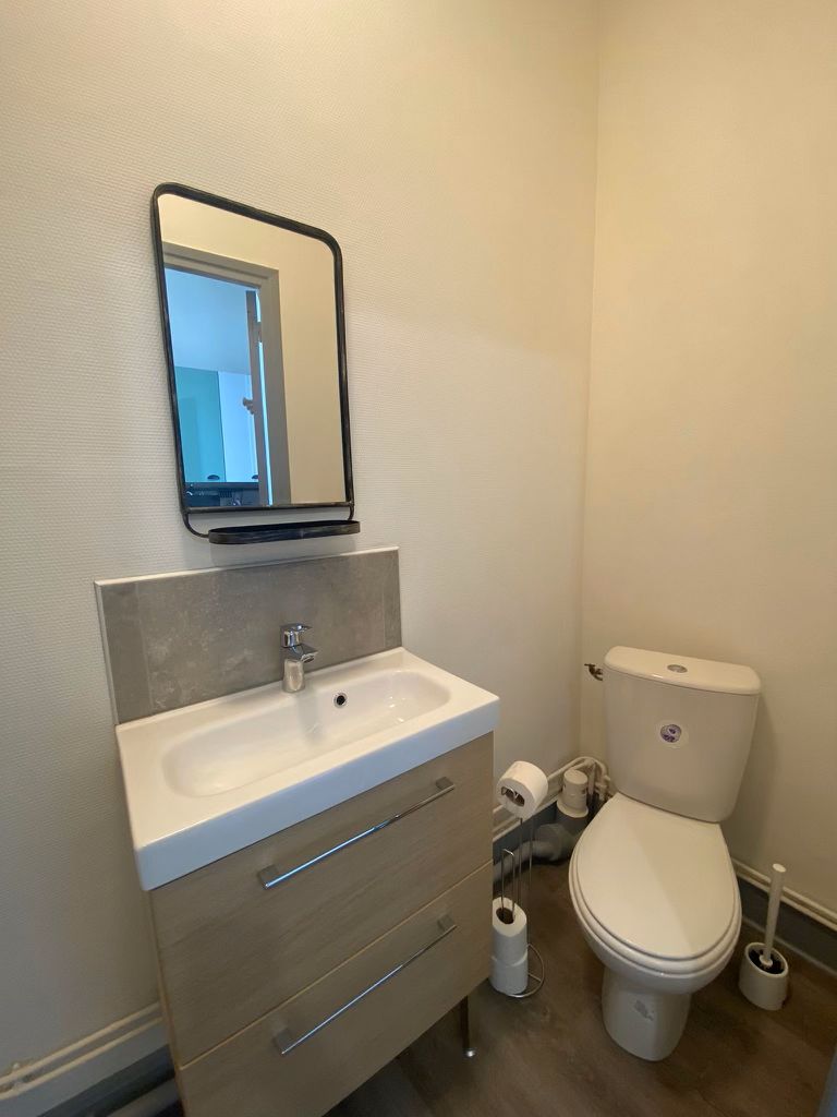 A bathroom with a white sink, mirror, and toilet.