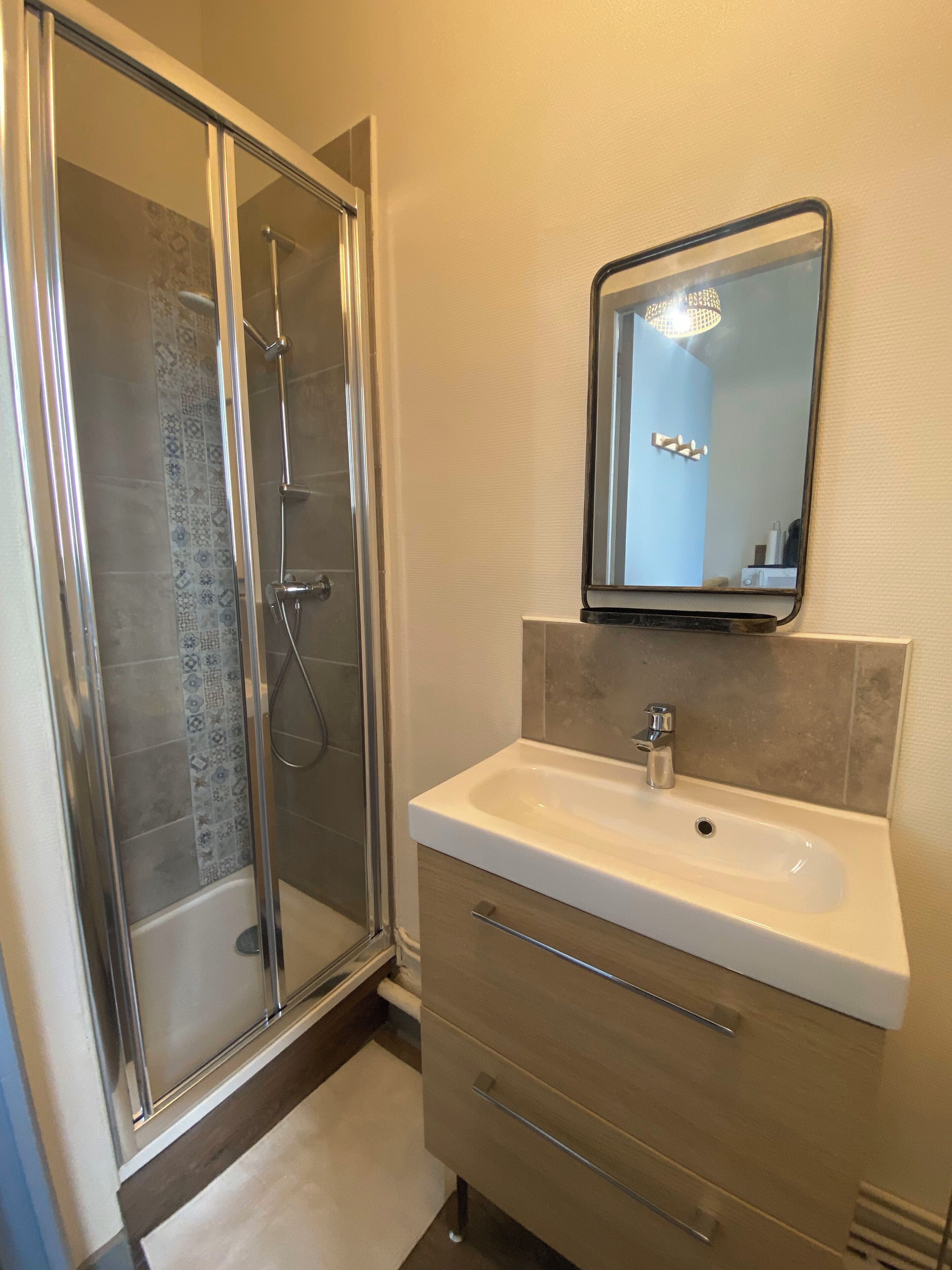 Un bagno con box doccia in vetro, un lavandino bianco e uno specchio sopra.