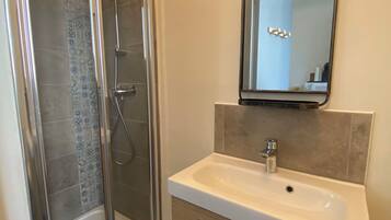 Un bagno con box doccia in vetro, un lavandino bianco e uno specchio sopra.