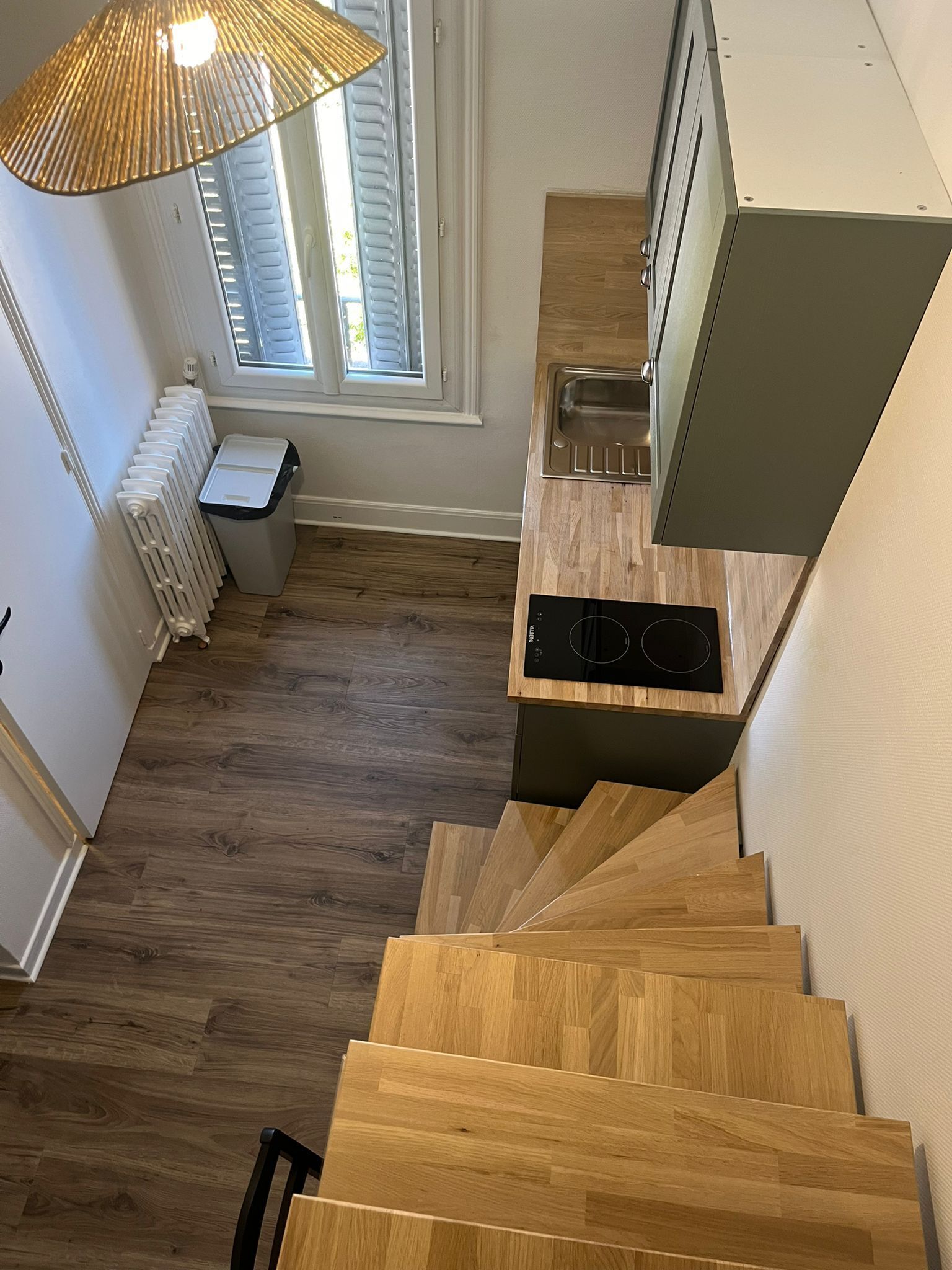 Cocina compacta con estufa integrada, un lavabo y una ventana con persianas.