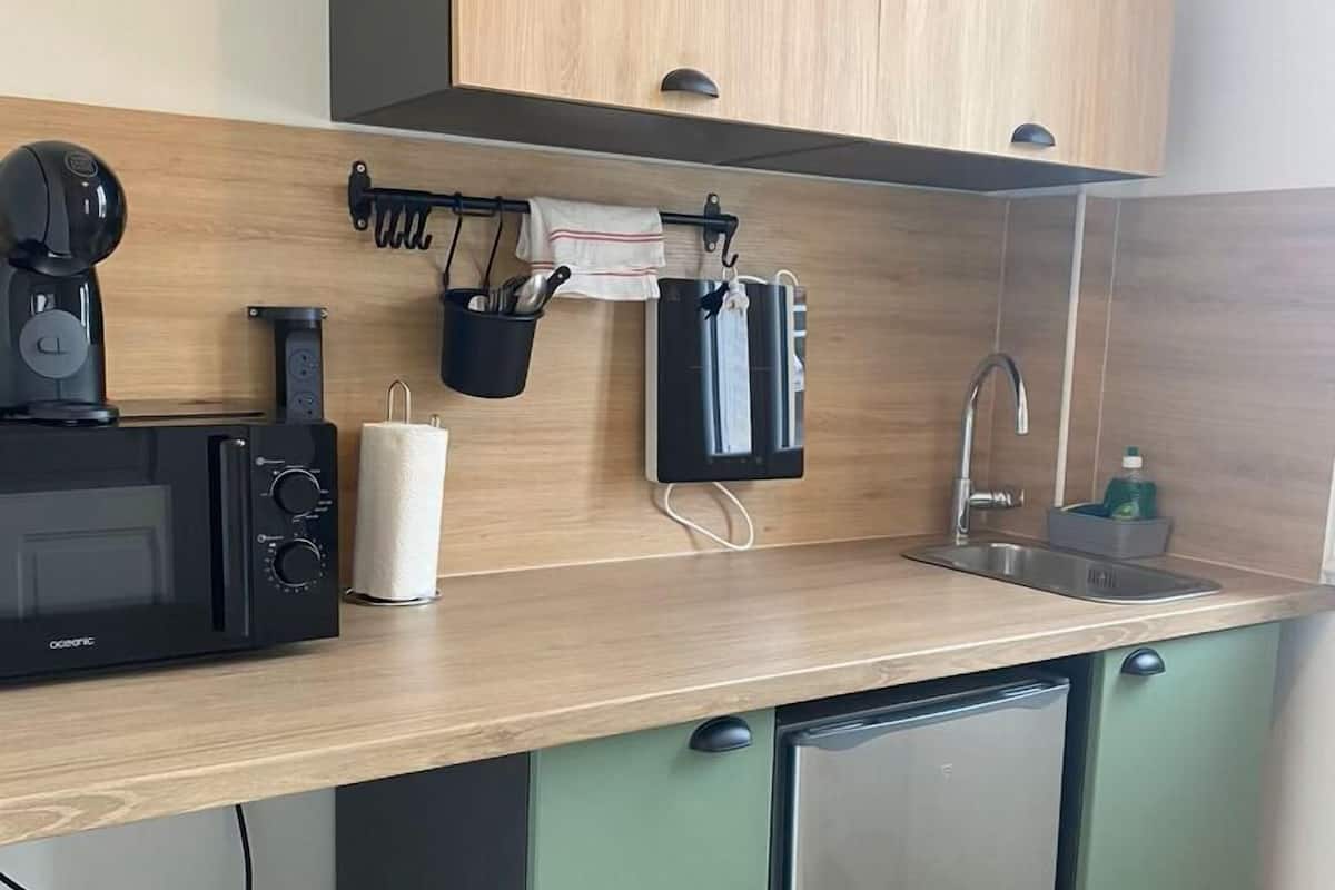 A compact kitchen with a microwave, coffee maker, and a sink.