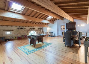 A spacious loft with high ceilings, wooden beams, and a foosball table.