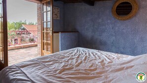 Ein Schlafzimmer mit einem Bett, einem Fenster und einer Tür, die zu einem Außenbereich führt.