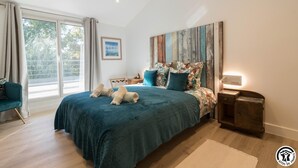 A modern bedroom with a large bed, a desk, and a chair. There is a window with curtains, a painting on the wall, and a wooden floor. - Villa La Sauzière - BUZET SUR TARN (BUZET SUR TARN)