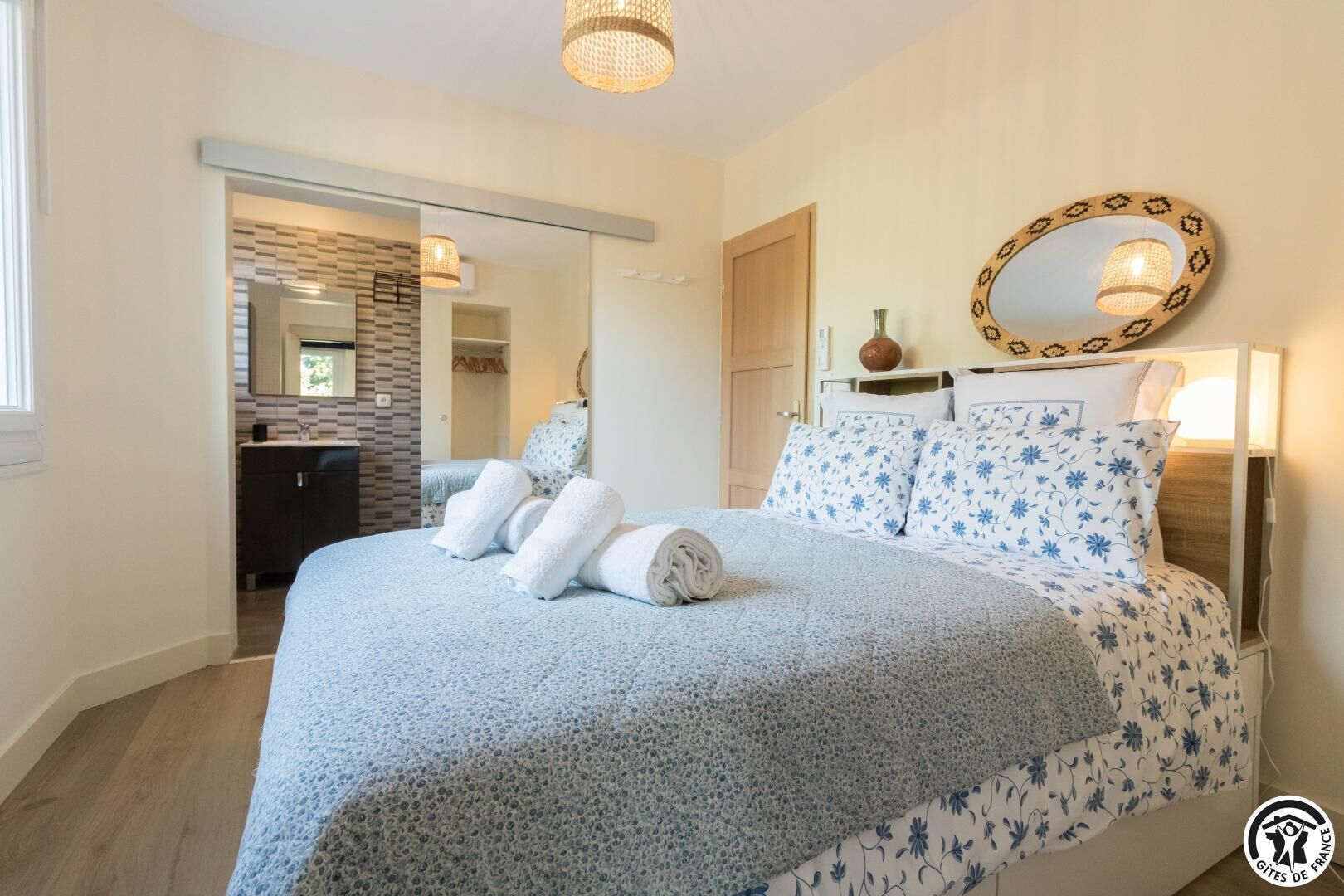 Una camera da letto con un letto grande, uno specchio e un bagno visibile attraverso una porta aperta.