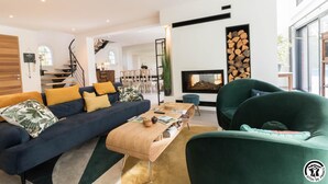 A modern living room with a sofa, armchairs, a coffee table, and a fireplace. - Villa La Sauzière - BUZET SUR TARN (BUZET SUR TARN)