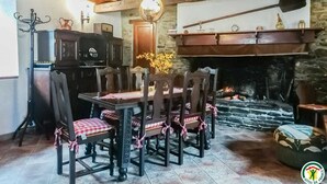 A rustic dining room with a stone fireplace, wooden beams, and a traditional stove. - Chez Marthe - Melles (Melles)
