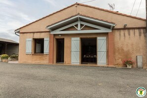 Un edificio de dos pisos con techo plano, una entrada central con puerta y dos ventanas con persianas.