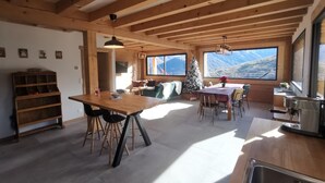 A spacious kitchen with a wooden table and bar stools, large windows with mountain views, and a cozy seating area with a Christmas tree. - Pyrenean chalet Fryo - Poubeau (Poubeau)