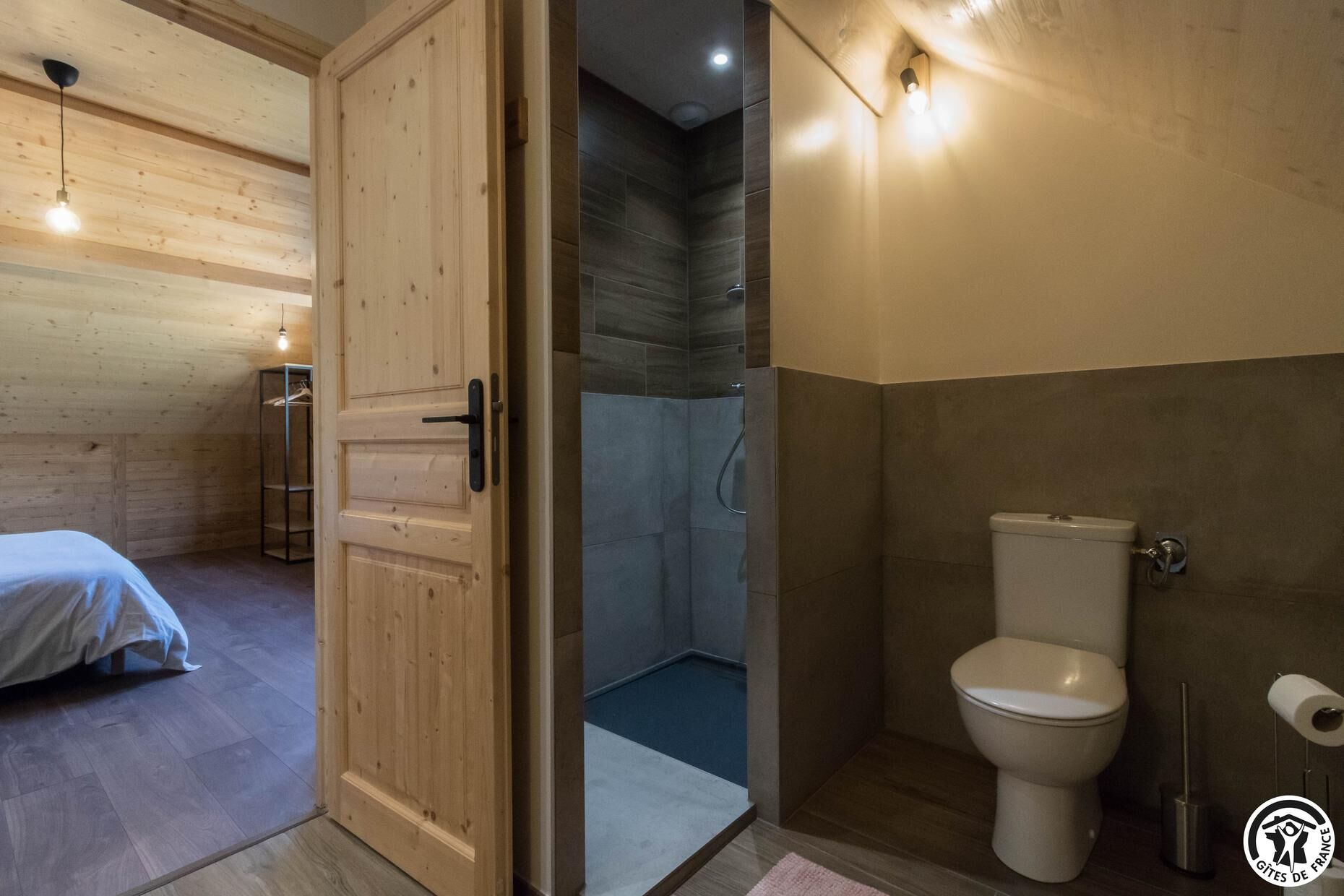 Un intérieur en bois comprenant un lit, une porte en bois, une douche et des toilettes.