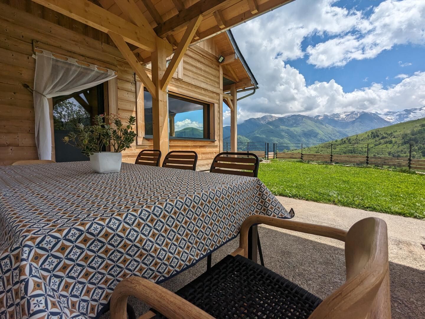 Eine Holzhütte mit Bett, Stühlen und Bergblick.