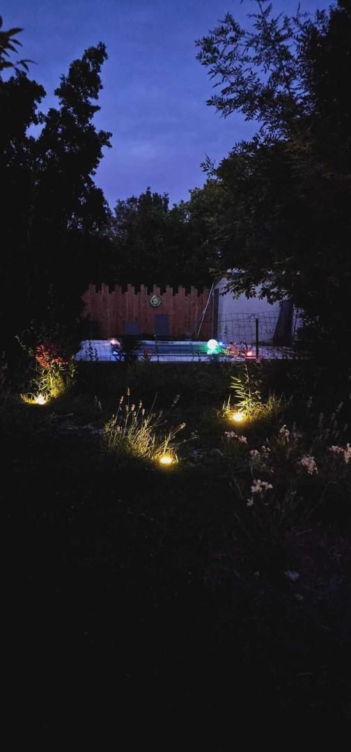 Un jardín con valla de madera, un sendero y algunas flores.
