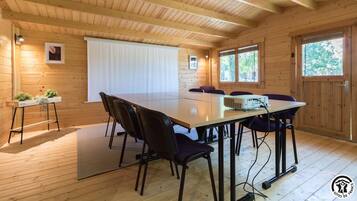 A wooden cabin with a large dining table, chairs, and a projector.