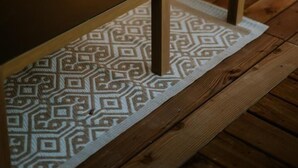 Un plancher en bois, un tapis à motifs, une table et deux chaises avec des coussins.