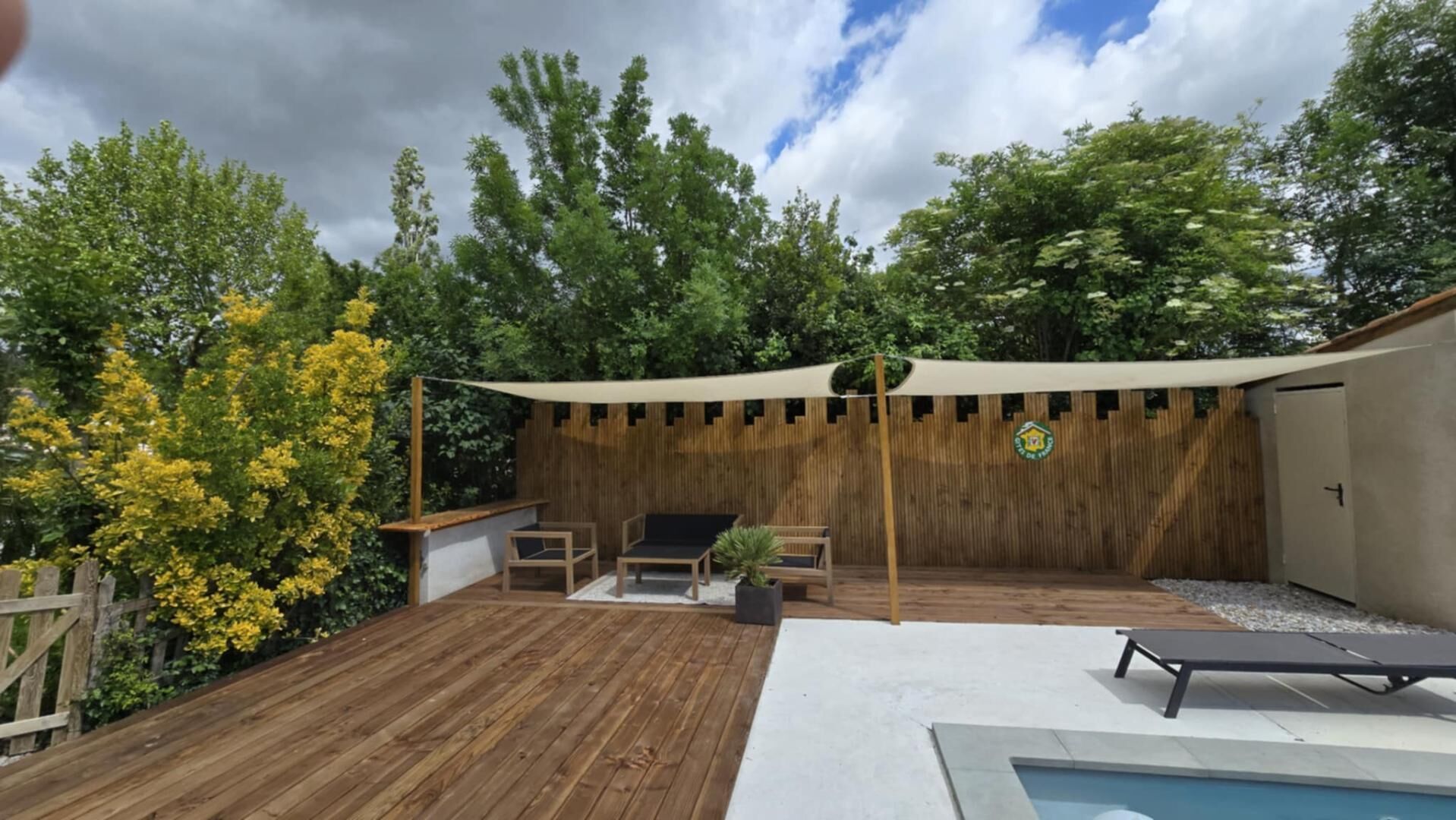A wooden deck with outdoor seating, a pool, and a covered area with a wooden fence.
