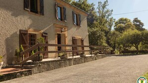 A two-story building with a stone facade, wooden shutters, and a gravel driveway.