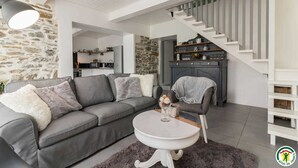 A modern living room with a grey sofa, a white coffee table, and a staircase leading to a dining area. - Gîte de Pene Blanque - Arbas (Arbas)