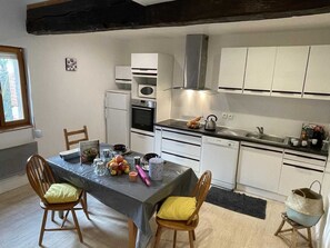 Une cuisine compacte avec des meubles blancs, un four encastré, un four à micro-ondes et un évier.