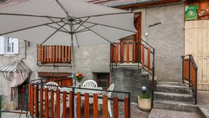 A house with a wooden staircase, a white chair, and a table with a tablecloth. - Au Cabanous - BOUTX - Gîte (BOUTX)