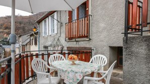 A patio with a table and chairs, a bowl of fruit, and a view of a mountain.