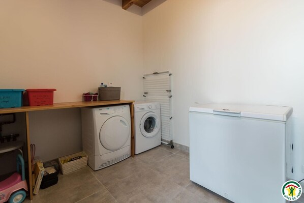 Une buanderie équipée d’un lave-linge, d’un sèche-linge et d’un petit réfrigérateur.
