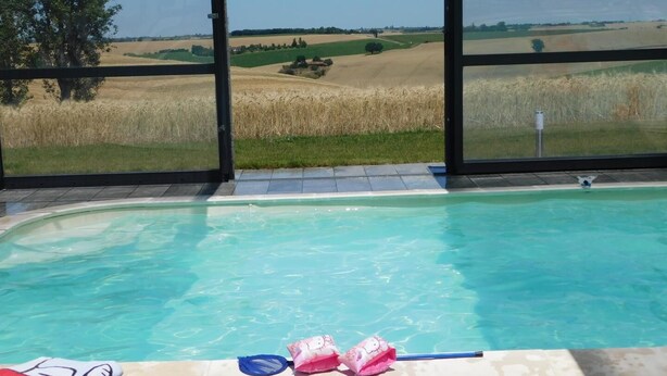 Ein Swimmingpool mit Blick auf ein Weizenfeld und einen Baum.